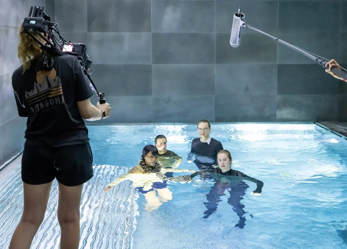 Filmschauspielschule Zürich – Schauspielstudierende drehen eine praxisnahe Filmszene im Wasser mit professionellem Kamerateam, spezialisiert auf Film und Fernsehen.