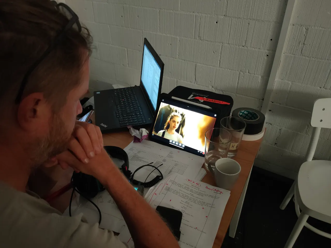 Dozent analysiert eine Filmszene auf einem Tablet, mit Drehbuchnotizen und Laptop an der Filmschauspielschule Zürich